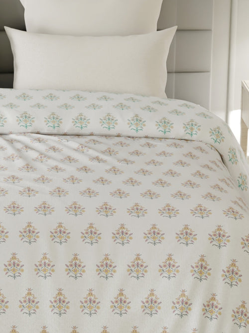 Floral patterned bedspread on a bed with white pillows.