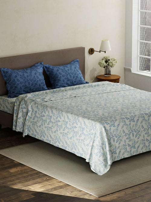 Bed with floral bedding and blue pillows in a bedroom setting.